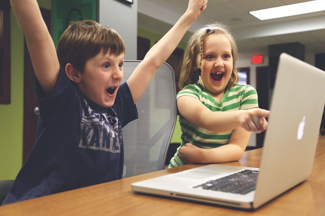 Deux enfants exprimant leur joie devant un ordinateur portable